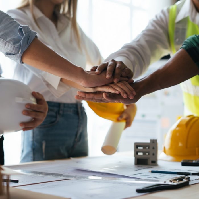 Construction workers, architects and engineers shake hands after completing an agreement in an office facility, successful cooperation concept.