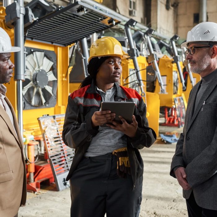 African female foreman using digital tablet in her work during her meeting with engineers in factory