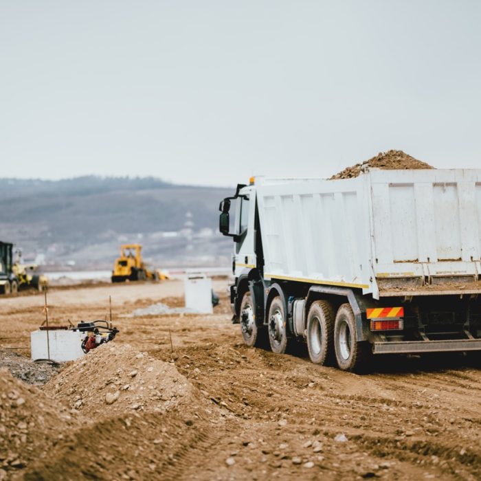 Industrial dumper trucks working on highway construction site, loading and unloading earth. heavy duty machinery activity