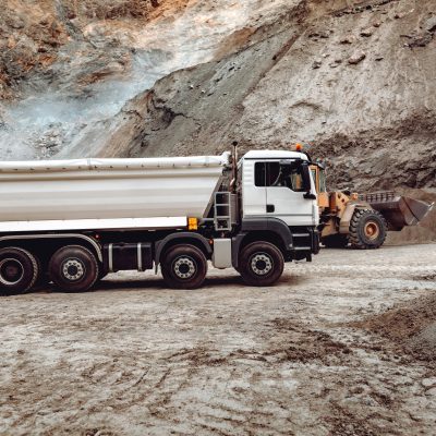 Industrial dumper trucks working on highway construction site, loading and unloading gravel and earth. heavy duty machinery activity and works
