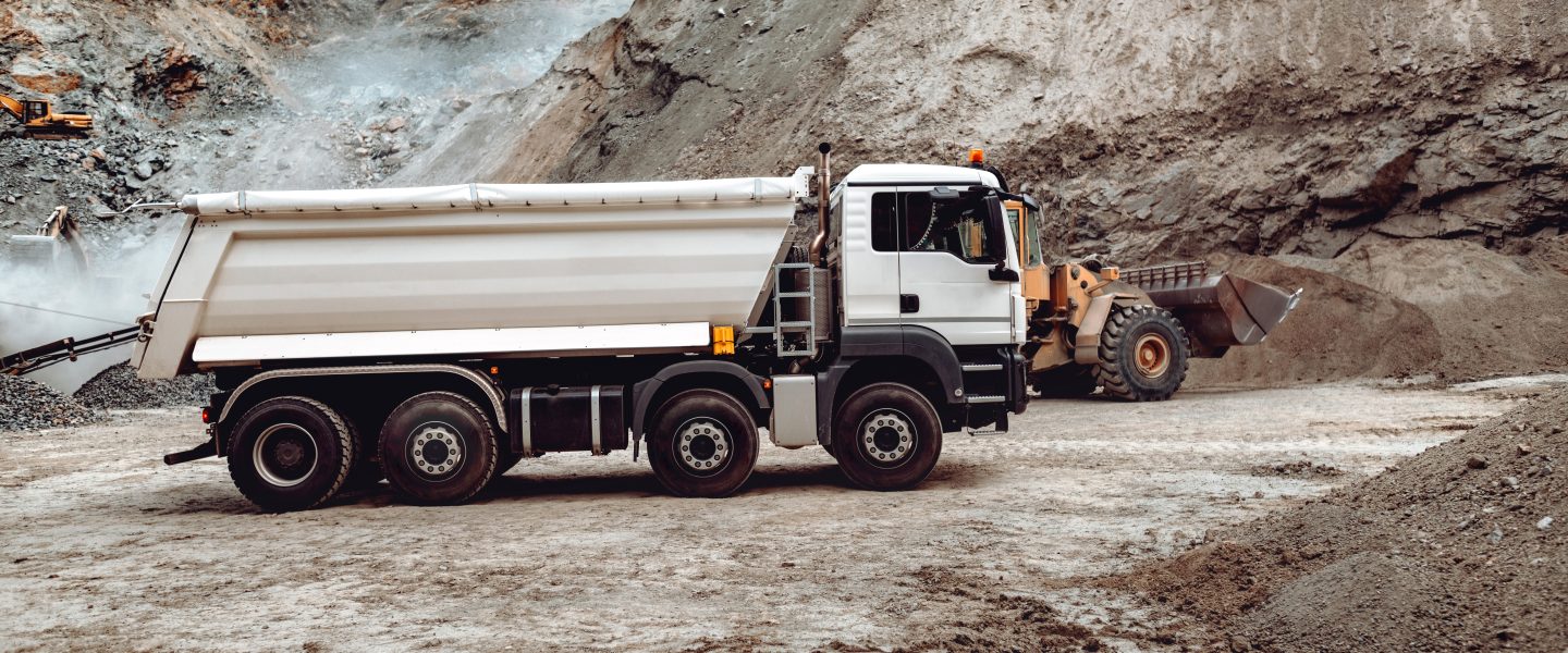 Industrial dumper trucks working on highway construction site, loading and unloading gravel and earth. heavy duty machinery activity and works
